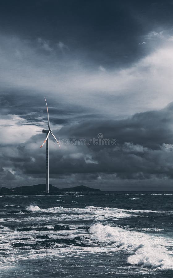 Scenery of stormy waves and gloomy sky with a lonely wind turbine in the background