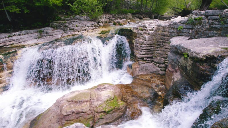 scenic drone shot of a small and fast waterfall on enormous rocky ledges