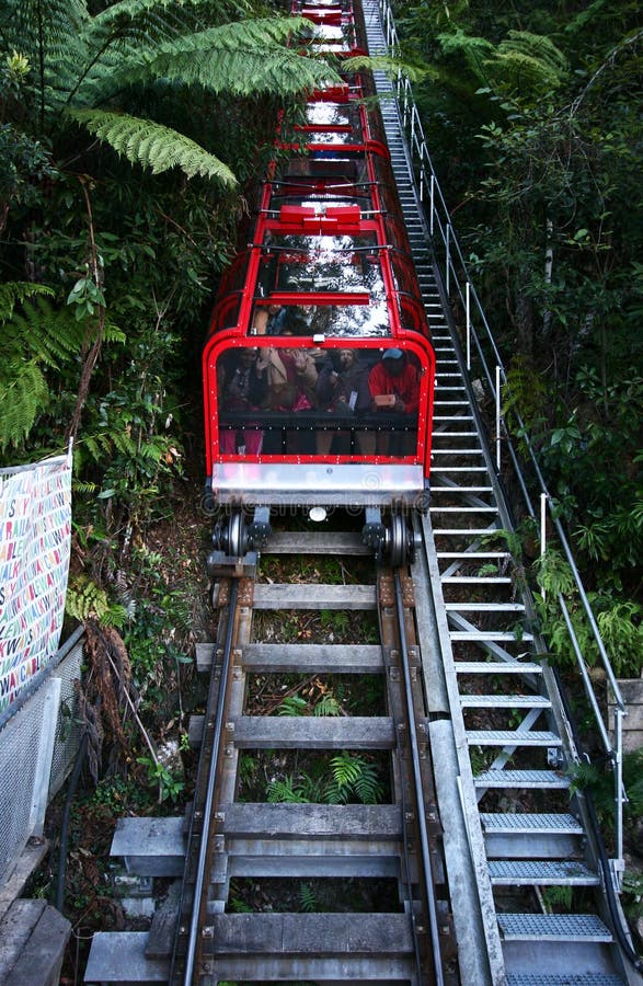 Single-track railway with red cable car descending downhill on mountainside with vegetation in Blue Mountains National Park
