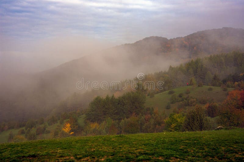 Scenic landscape of mountains shrouded in misty fog near a lush forest. Banska Bystrica, Slovakia.