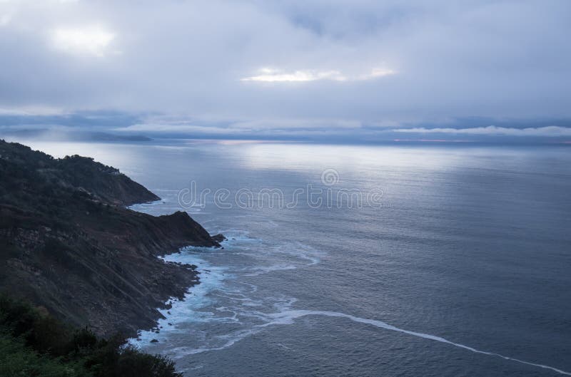 Scenic mysterious mystical seascape landscape with sun rays piercing through clouds sky sunset on atlantic shoreline in deep blue royalty free stock photos