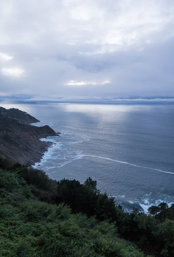 Scenic mysterious mystical seascape landscape with sun rays piercing through clouds sky sunset on atlantic shoreline in deep blue stock photos