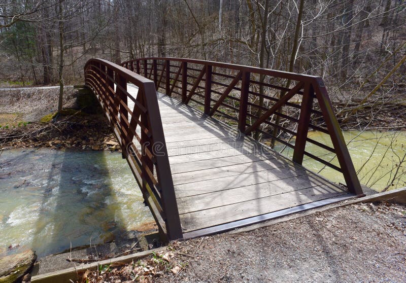 Scenic Red Metal And Wooden Bridge Over A Creek In A Forest Stock