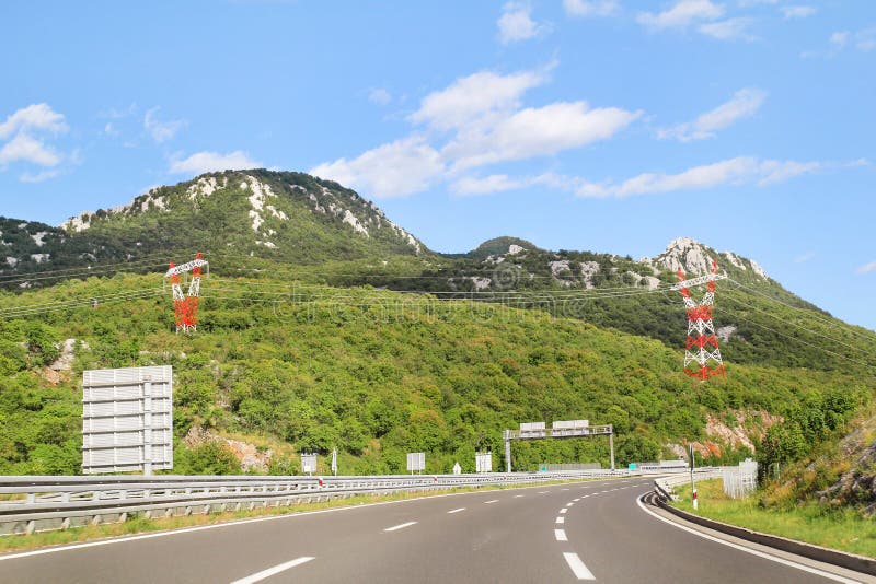 Scenic view on highway road leading through in Croatia, Europe / Electrical transmission towers, sky and clouds in background.