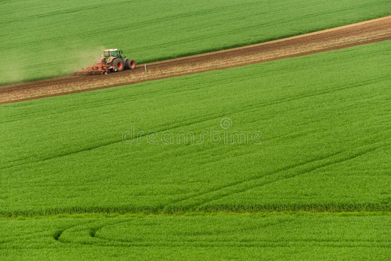 Scenic View of Modern Farming Tractor Which Plowing Green Field. Agriculture  Tractor Cultivating Wheat Field and Creating Green Ab Stock Photo - Image  of field, environment: 105839684