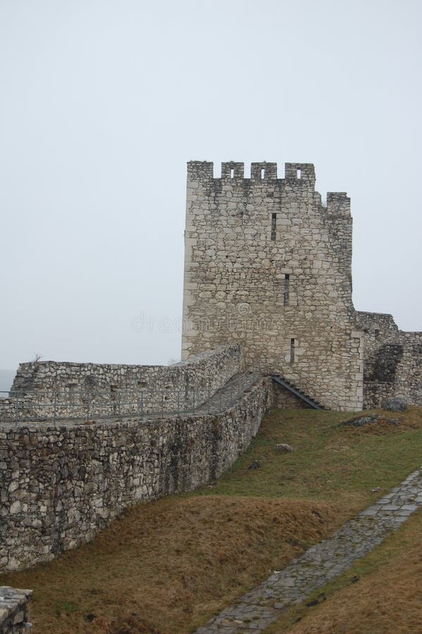 Scénický pohled na starý kamenný evropský hrad s šedou mlhou na pozadí