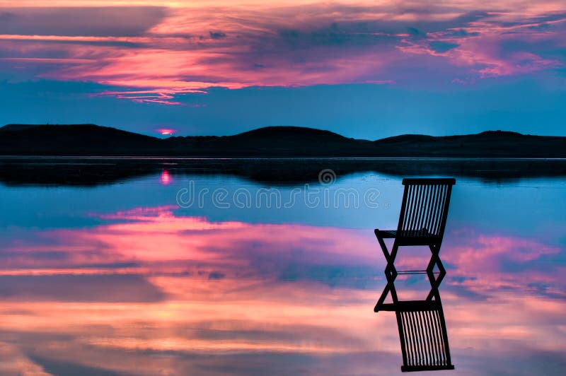 Scenic view of sunset with chair in calm water