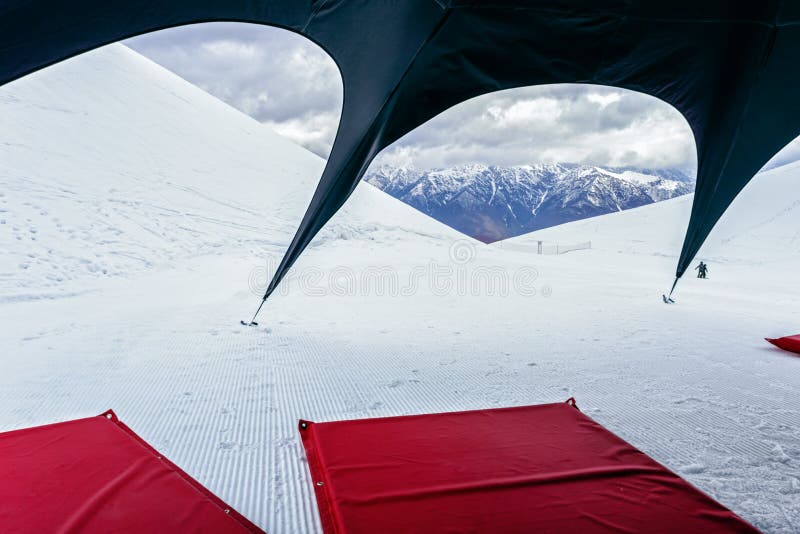 Scenic winter mountain peak landscape with red mattresses on snow under black tent. Camping activities and leisure at ski resort. Concept of holiday, vacation royalty free stock photo Scenic winter mountain peak landscape with red mattresses on snow under black tent. Camping activities and leisure at ski resort. Concept of holiday, vacation royalty free stock photo