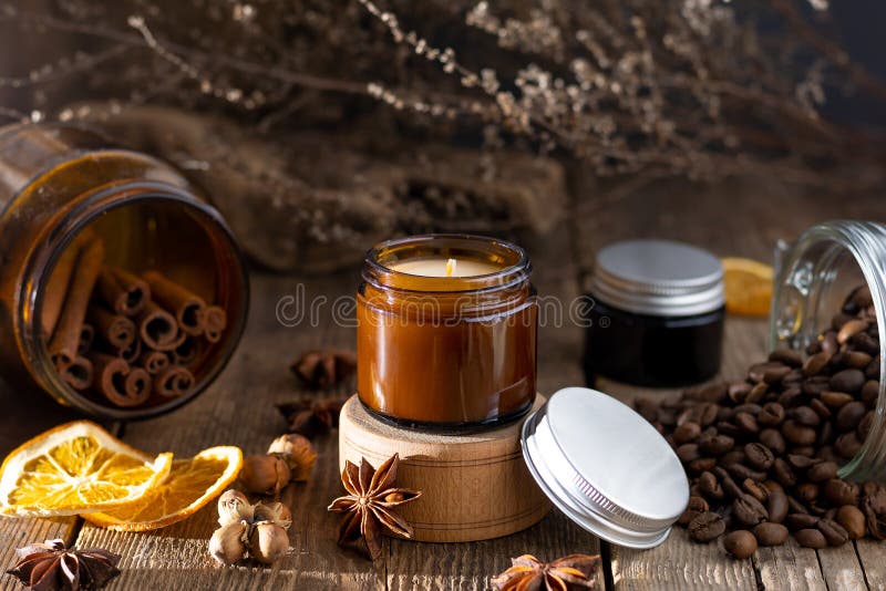 Scented candle in a glass jar. Coffee aroma. Star anise, cinnamon sticks, dried orange. Still life. Coffee beans. Brown