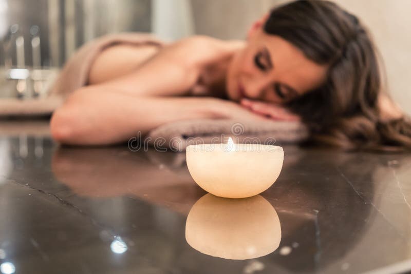 Scented candle next to young woman on marble massage table at sp royalty free stock images Scented candle next to young woman on marble massage table at sp royalty free stock images