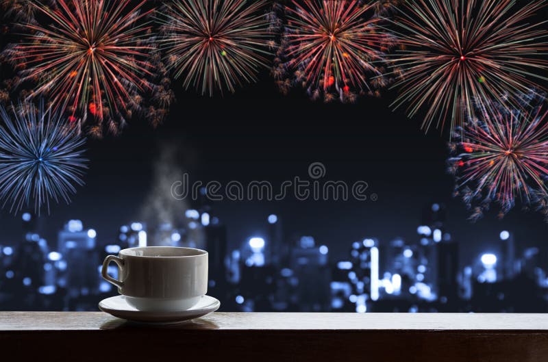 Schale heiße Getränke auf hölzernem Schreibtisch mit neuem Jahr feiern Feuerwerke, blaues defocus Bokeh-Licht von Gebäuden in der
