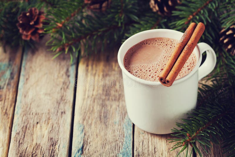 Schale heißer Kakao oder heiße Schokolade auf hölzernem Hintergrund mit Tannenbaum und Zimtstangen, traditionelles Getränk für Wi