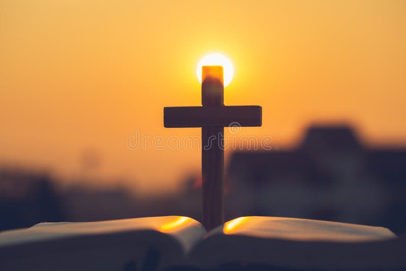 Schattenbild des Kreuzes auf der heiligen Bibel, des Religionssymbols im Licht und der Landschaft über einem Sonnenaufgang, Hinte