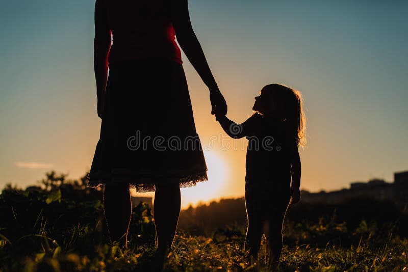 Schattenbild des Mutter- und Tochterhändchenhaltens bei Sonnenuntergang