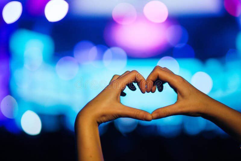 Schattenbild eines Herzens formte Hände und Menge des Publikums am Livekonzert, helles belichtet ist Energie des Musikkonzerts lizenzfreie stockfotografie Schattenbild eines Herzens formte Hände und Menge des Publikums am Livekonzert, helles belichtet ist Energie des Musikkonzerts lizenzfreie stockfotografie