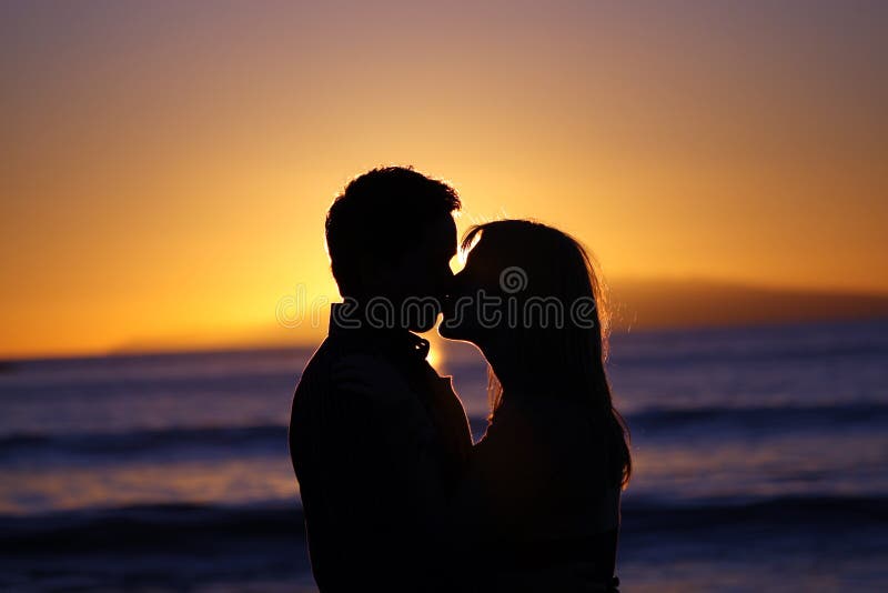 Schattenbild eines jungen Paares, das am Strand küßt