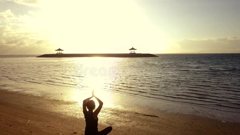 Schattenbildfrau, die Yoga am Strand tut