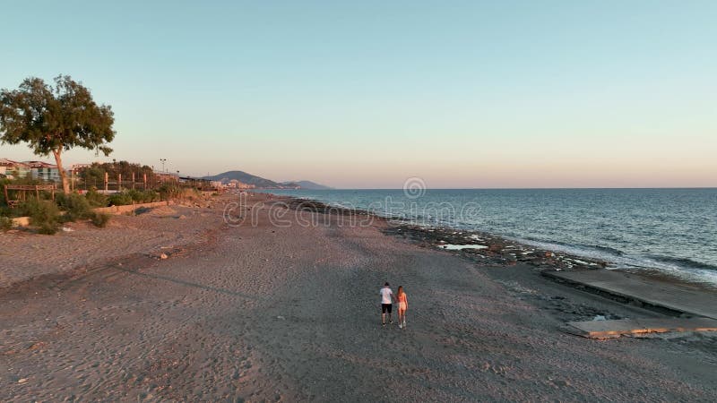 Schattig stel dat op zonsondergang 4.000 op het strand loopt