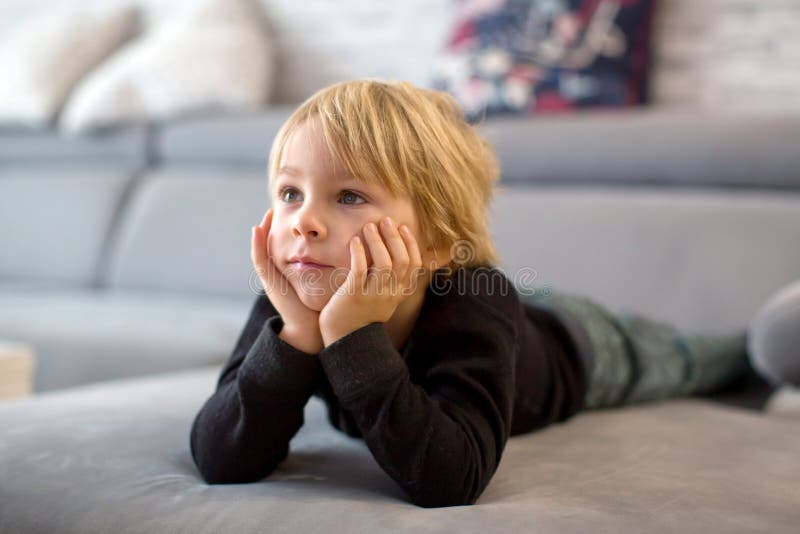 Cute blond child, toddle boy, watching TV with his pet maltese dog at home. Cute blond child, toddle boy, watching TV with his pet maltese dog at home