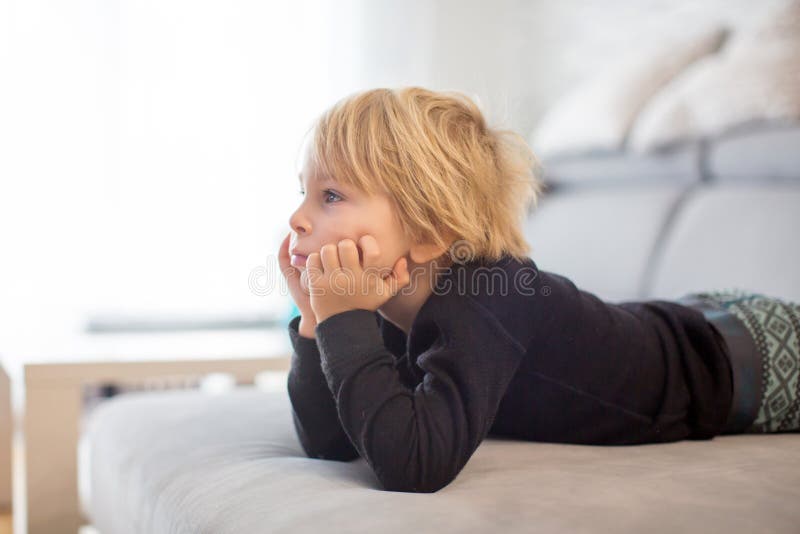 Cute blond child, toddle boy, watching TV with his pet maltese dog at home. Cute blond child, toddle boy, watching TV with his pet maltese dog at home