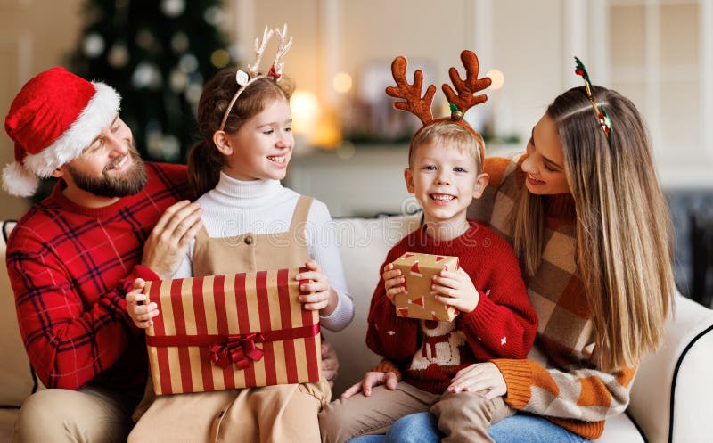 Schattige , gelukkige kleine kinderen broers en zussen die kerstcadeaus krijgen terwijl ze zitten met jonge liefhebbende ouders
