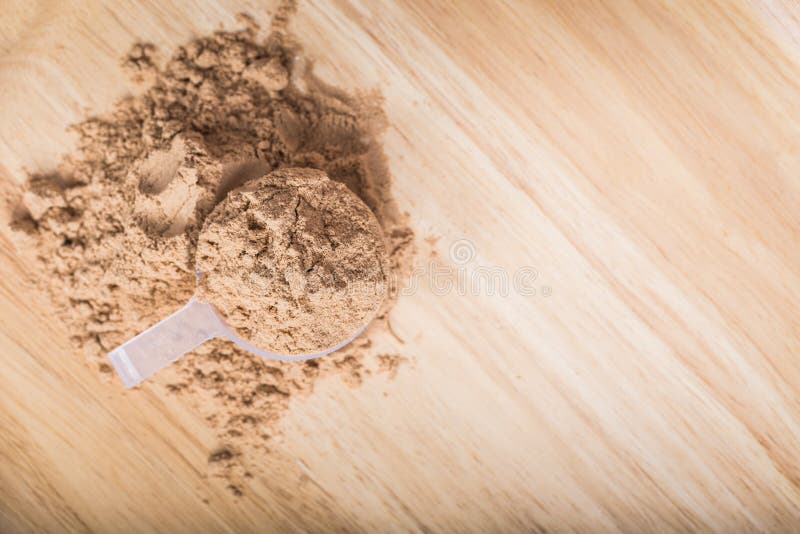 Schaufel des Molkeproteins auf einer hölzernen Platte stockbild Schaufel des Molkeproteins auf einer hölzernen Platte stockbild