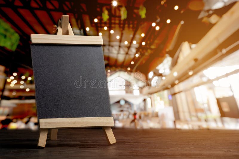 empty food menu board with black mockup space on a vintage wooden table with blurred restaurant background. empty food menu board with black mockup space on a vintage wooden table with blurred restaurant background