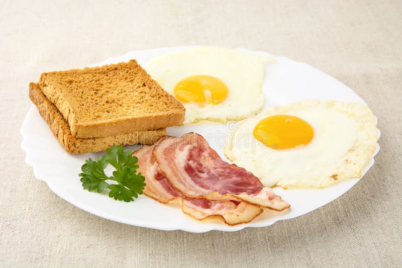 Scheibe des Speckes mit zwei Eiern auf der Platte mit Toast lizenzfreie stockfotografie Scheibe des Speckes mit zwei Eiern auf der Platte mit Toast lizenzfreie stockfotografie