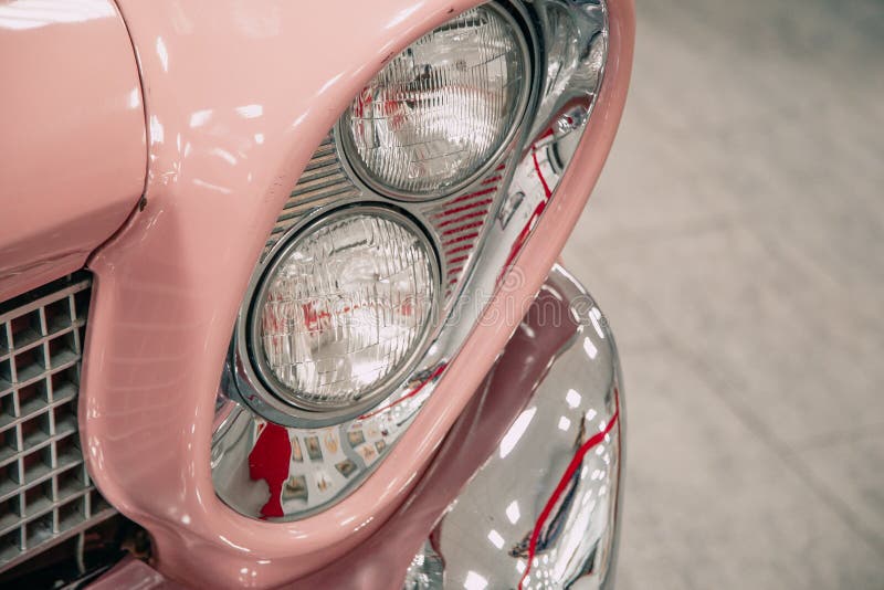 Scheinwerfer eines Retro- Autos rosa Farbe in einem Autosalon. Nahaufnahme lizenzfreie stockfotografie
