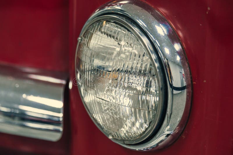 Scheinwerfer eines Retro- Oldtimer in Rot in einem Autosalon. Scheinwerfer eines Retro- Autos in Rot im Autosalon. Wiederaufbau