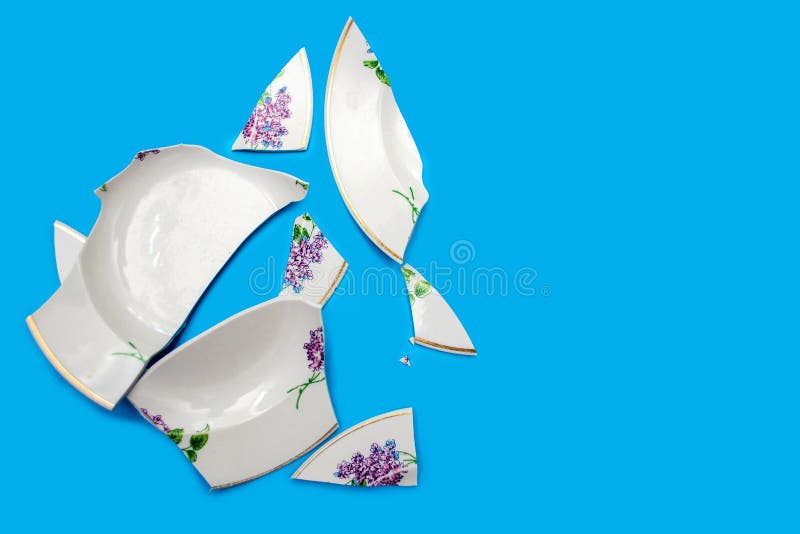 Shards of a broken plate on a blue background. Small pieces of chopped dishes. Shards of a broken plate on a blue background. Small pieces of chopped dishes.