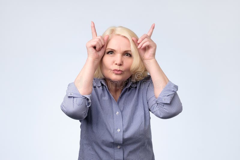 Scherzende ältere Blondine, die Hörner herstellen Schönes Tanzen der jungen Frau der Paare stockfoto Scherzende ältere Blondine, die Hörner herstellen Schönes Tanzen der jungen Frau der Paare stockfoto