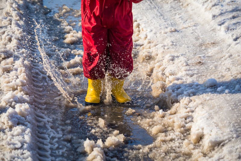 Scherzi nei rainboots che saltano nella pozza del ghiaccio immagine stock libera da diritti Scherzi nei rainboots che saltano nella pozza del ghiaccio immagine stock libera da diritti