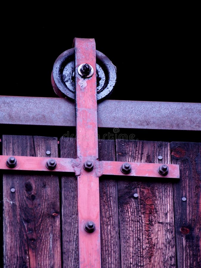 Schieben der Scheunentor, Detail eines Rades auf der Schiene, alte braunes Tor mit einem Metall, das Mechanismus, technische Lösung der Türreise verschiebt