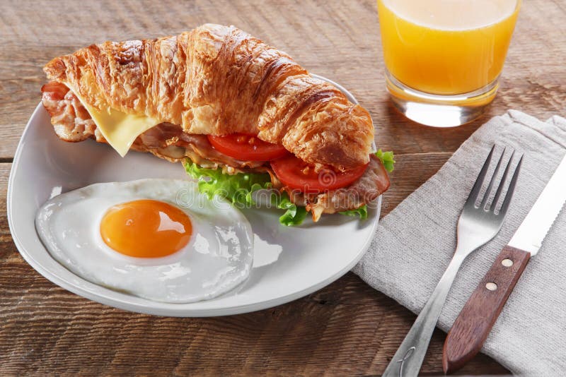 Schieben Sie Hörnchen mit gebratenem Speckkäsetomatenfrühstück und -ei ein lizenzfreies stockbild