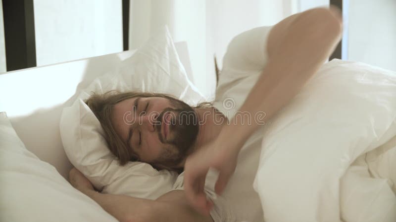 Schlafender Mann im Bett mit weißen Leinen am hellen Schlafzimmer stock video footage