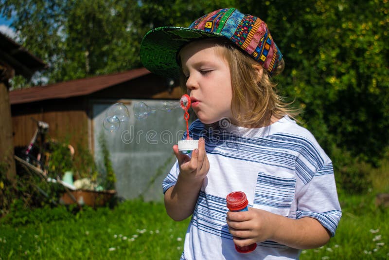 Schlagblasen des jungen blonden Jungen lizenzfreie stockbilder Schlagblasen des jungen blonden Jungen lizenzfreie stockbilder