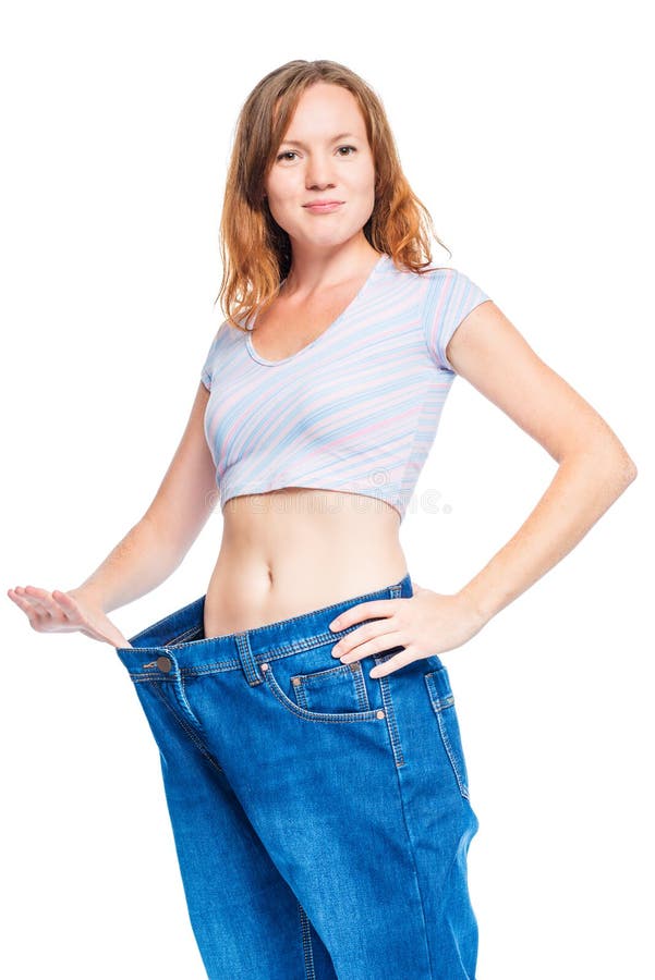 Schlankes rothaariges Mädchen, das alte Hosen nach verlierendem Gewicht zeigt lizenzfreies stockbild Schlankes rothaariges Mädchen, das alte Hosen nach verlierendem Gewicht zeigt lizenzfreies stockbild