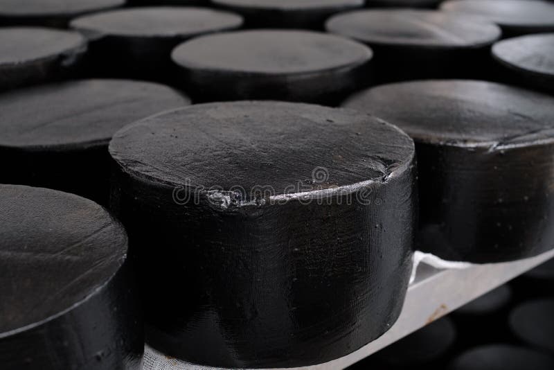 Schleifen des schwarzen Milchziegenkäses in einem Fabriklager. langfristige Reifung des Käse in einem besonderen Raum, bis das Pro lizenzfreie stockbilder