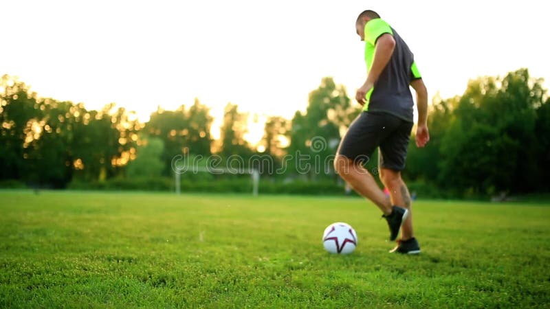 Schließen Sie herauf Beine und Füße des Fußballspielers in der Aktion, welche die schwarzen Schuhe trägt, die mit dem Ball laufen