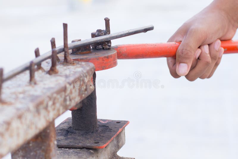 Schließen Sie herauf die Arbeitshand mit dem alten Eisenstangebieger lizenzfreies stockfoto Schließen Sie herauf die Arbeitshand mit dem alten Eisenstangebieger lizenzfreies stockfoto