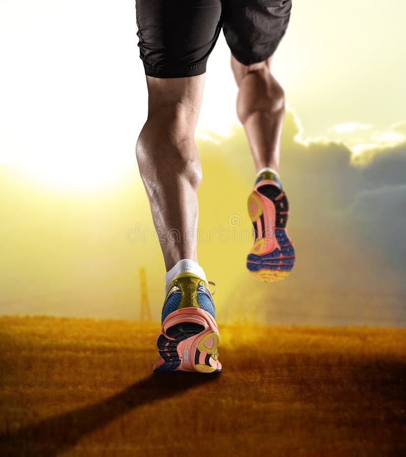 Schließen Sie herauf Füße mit den Laufschuhen und starken athletischen Beinen des Sportmannes rüttelnd im Eignungstrainings-Sonne