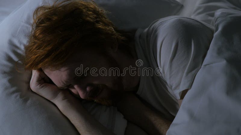 Schließen Sie oben vom Rothaarige-Bart-Mann, der im Bett schläft und sich entspannen