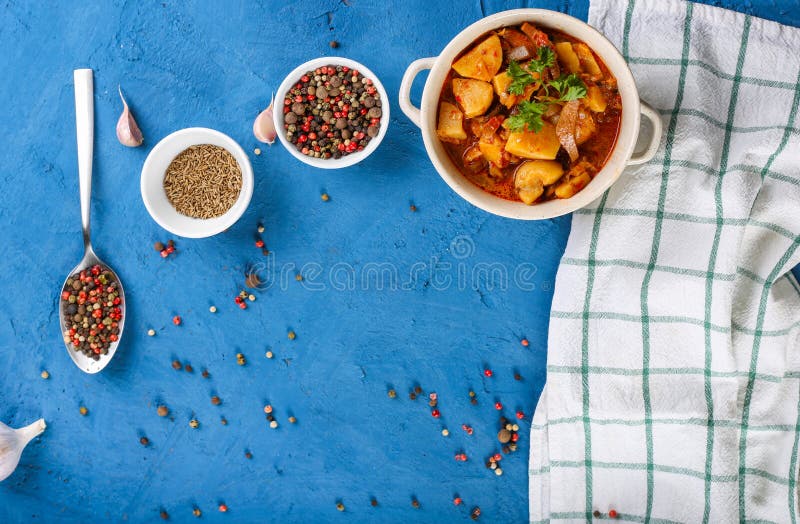 Schließen Sie oben vom Saltwort mit Fleisch, Kartoffeln, Tomatensauce und Pilzen in einer Schüssel auf einem blauen Steinhintergr stockbild Schließen Sie oben vom Saltwort mit Fleisch, Kartoffeln, Tomatensauce und Pilzen in einer Schüssel auf einem blauen Steinhintergr stockbild