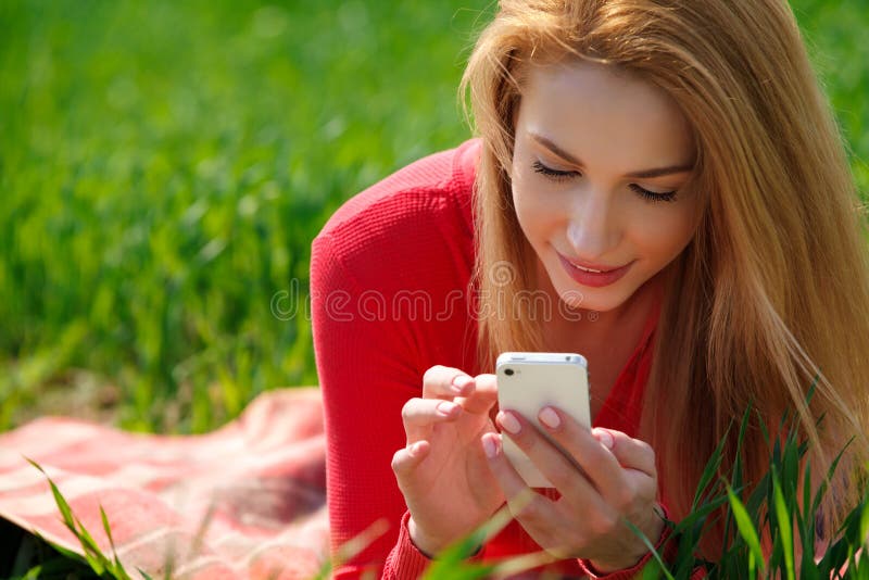Schließen Sie oben von der Frau, die intelligentes Mobiltelefon im Park verwendet lizenzfreie stockbilder Schließen Sie oben von der Frau, die intelligentes Mobiltelefon im Park verwendet lizenzfreie stockbilder