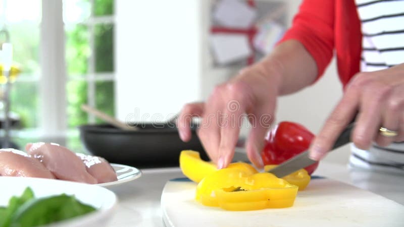 Schließen Sie oben von der Frau, die Pfeffer auf hölzernem Brett hackt