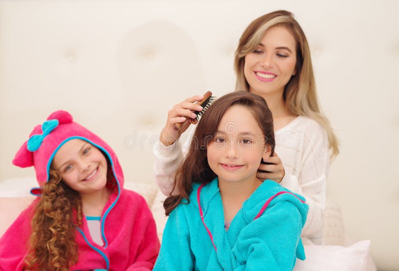 Schließen Sie oben von der jungen Mutter, die das Haar ihres wenig daugher brussing ist, das ein blaues bathtowel während ihr and stockfotos
