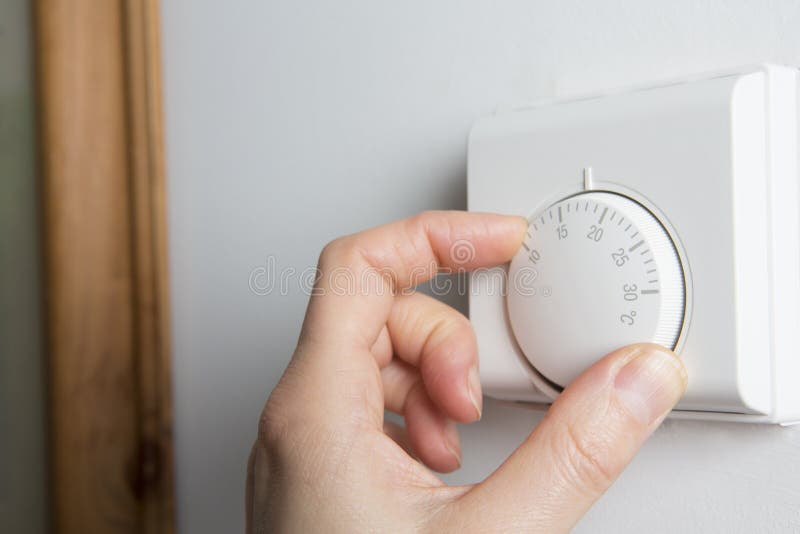 Schließen Sie oben von der weiblichen Hand auf Zentralheizungs-Thermostat