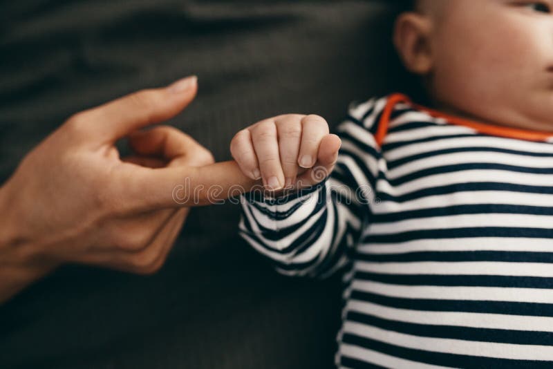 Schließen Sie oben von einem Baby, welches die Hand seiner Mutter hält stockbild Schließen Sie oben von einem Baby, welches die Hand seiner Mutter hält stockbild
