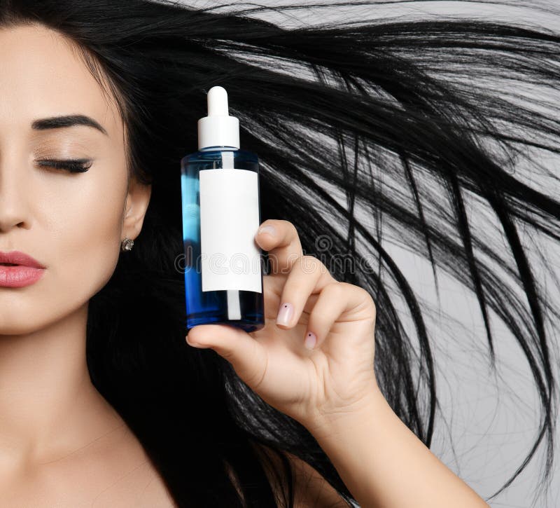 Schließen Sie oben von Frau Brunette mit geschlossenen Augen und das lange Haar, das im starken Wind flattert, hält eine Flasche lizenzfreie stockfotos Schließen Sie oben von Frau Brunette mit geschlossenen Augen und das lange Haar, das im starken Wind flattert, hält eine Flasche lizenzfreie stockfotos